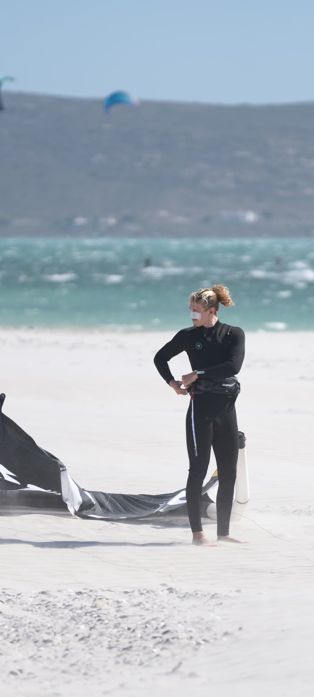 Anton Billstein, Kitelehrer und Mitgründer von Reise ins Blaue, im Neoprenanzug am Strand beim Aufbauen seines Kites
